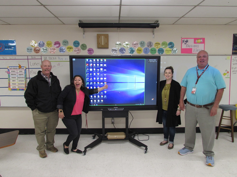 secondary teacher of the year giving thumbs up in front of her smartboard with administrators